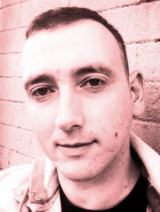 Casual close up author Cameron Macintosh, red-toned monochromatic image. 